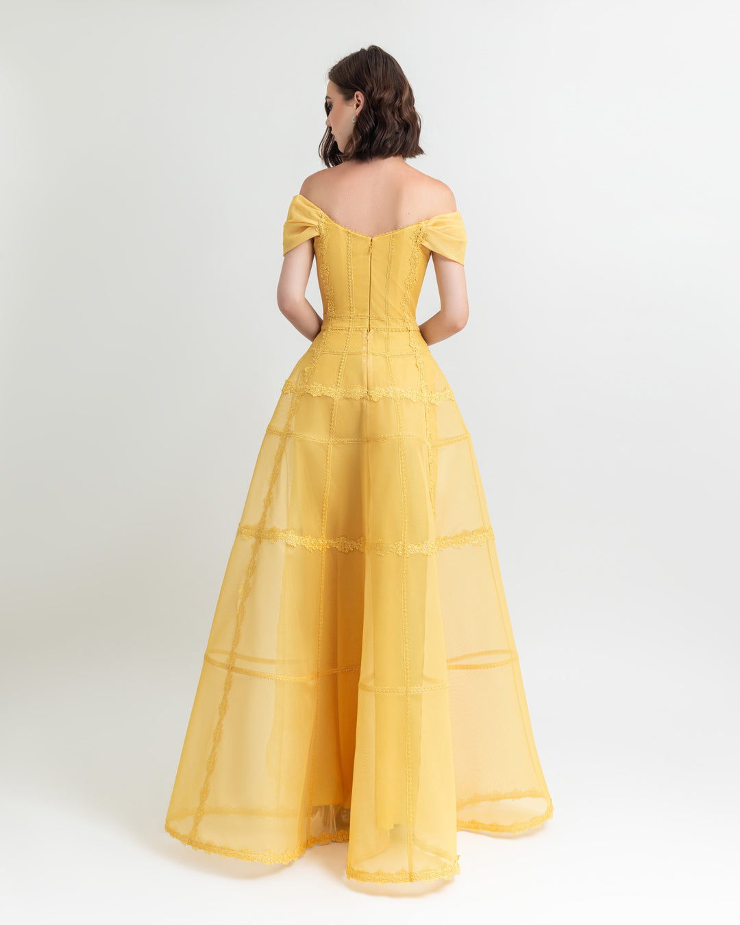 The back of an off-shoulders corset wide long evening dress in yellow mesh.