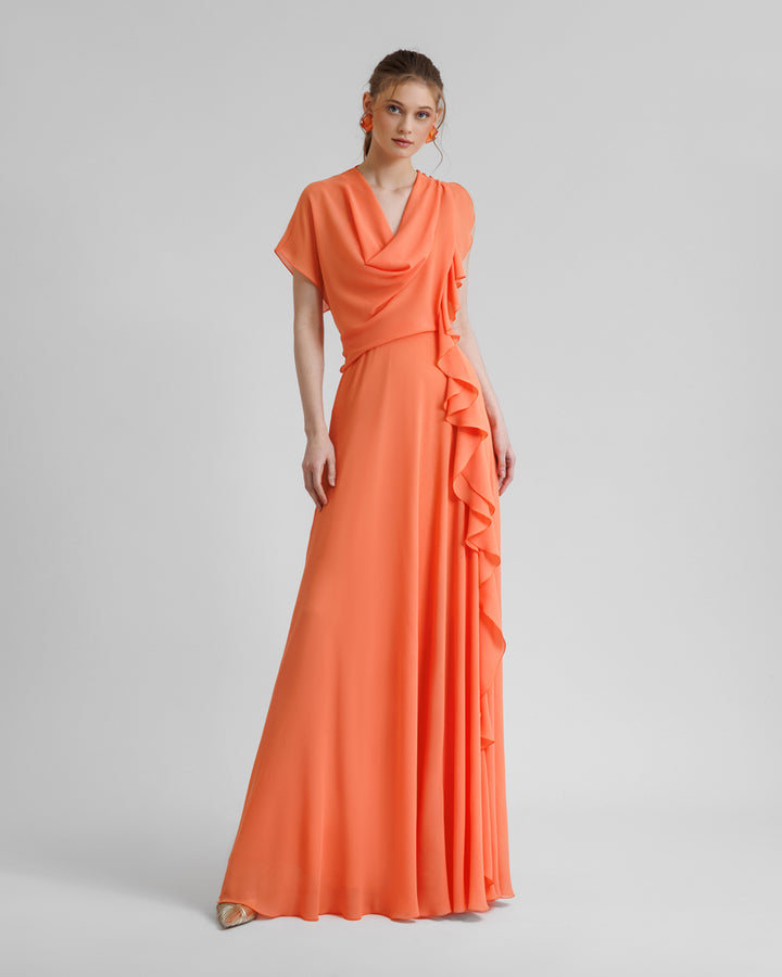 An asymmetrical flared orange dress with draping and ruffled details on the side.