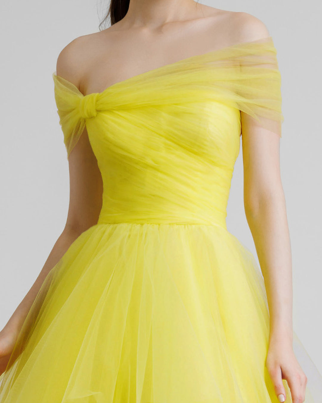 A close-up of an off-shoulder bow-cut design yellow evening dress.