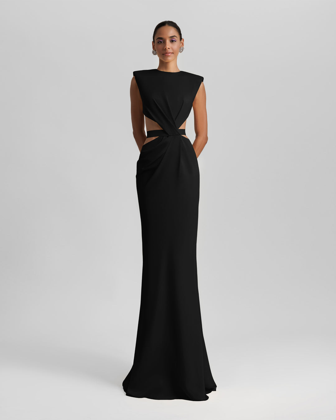 A slim-cut black dress featuring padded shoulders, draping and cut-outs on the waist, and an open back.