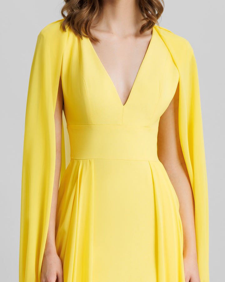 A close-up of a V-neckline long yellow evening dress with cape-like draped sleeves.