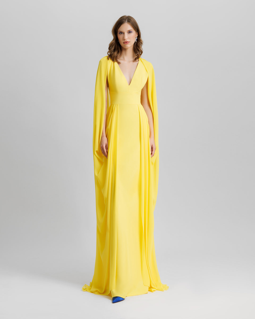 A V-neckline long yellow evening dress with cape-like draped sleeves.