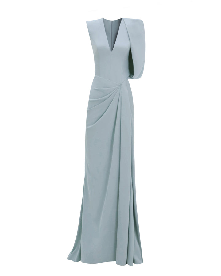 An asymmetrical teal evening dress with a bolero-like sleeve, a draped skirt and a slit on the side.