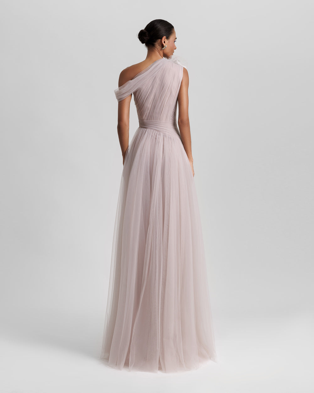 The back of a full tulle long evening lilac dress, with an asymmetrical neckline, and draping design on the bodice.