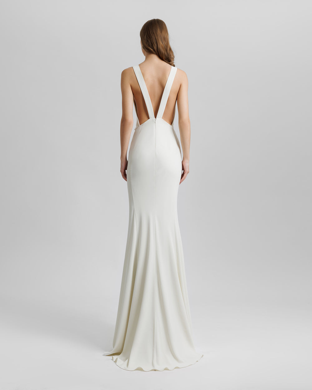 The back of a slim-cut cream evening dress featuring an alluring open back with V-shaped straps.