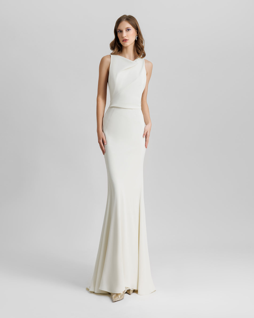 A slim-cut cream evening dress features captivating draping on the neckline and waist.