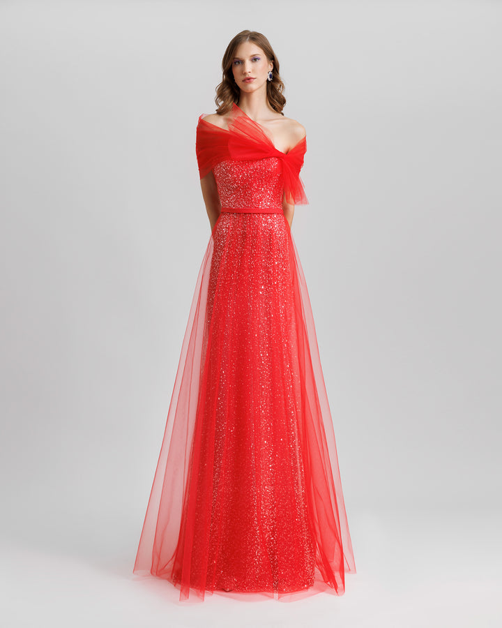 An off-the-shoulders red tulle dress with a beaded underlayer and a bow design.