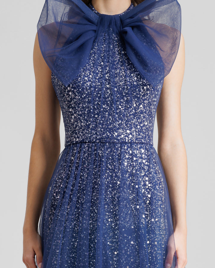 A close-up of an halter-neck blue dress with a bow design and a beaded underlayer.