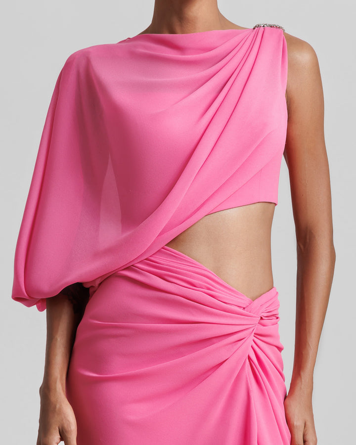 A close-up of an asymmetrical pink evening dress with a draped sleeve, cut out on the waist, and a draped skirt.