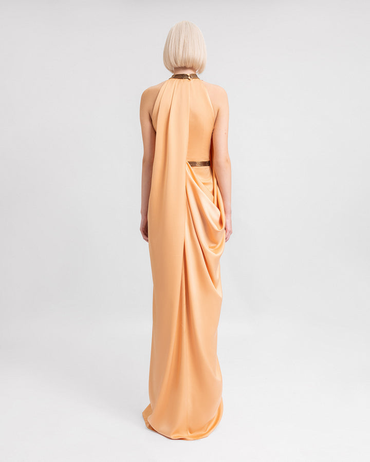 The baCK OF a loose-cut evening dress in peach satin featuring a beaded collar and belt, and draping on the back.