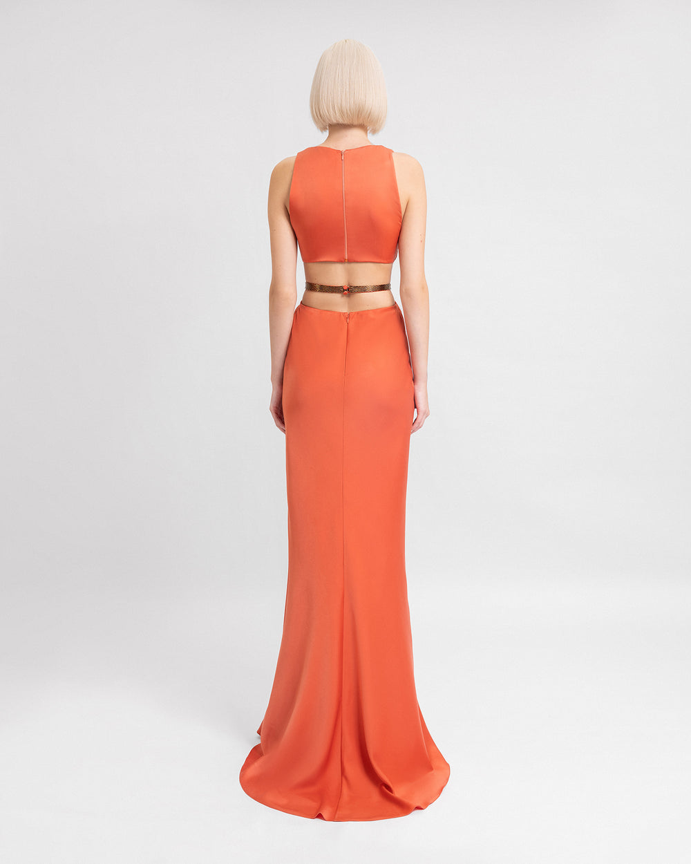 The back of a coral satin evening dress with a beaded belt and a back cut-out.