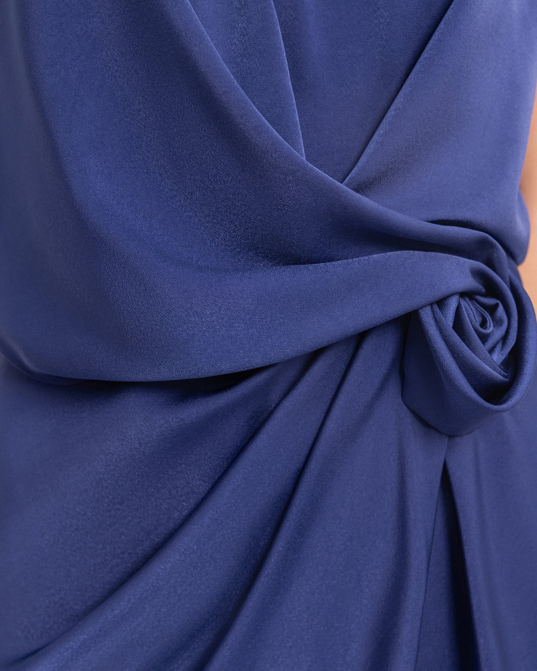 A close-up of a draped navy blue evening dress.