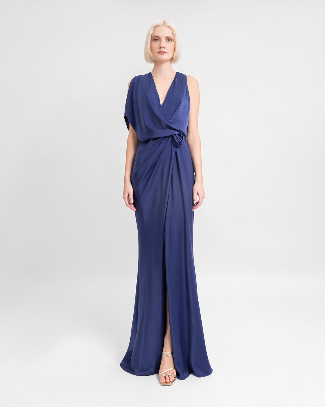 A draped navy blue evening dress featuring a V-neckline, asymmetrical sleeves, and a slit at the front.