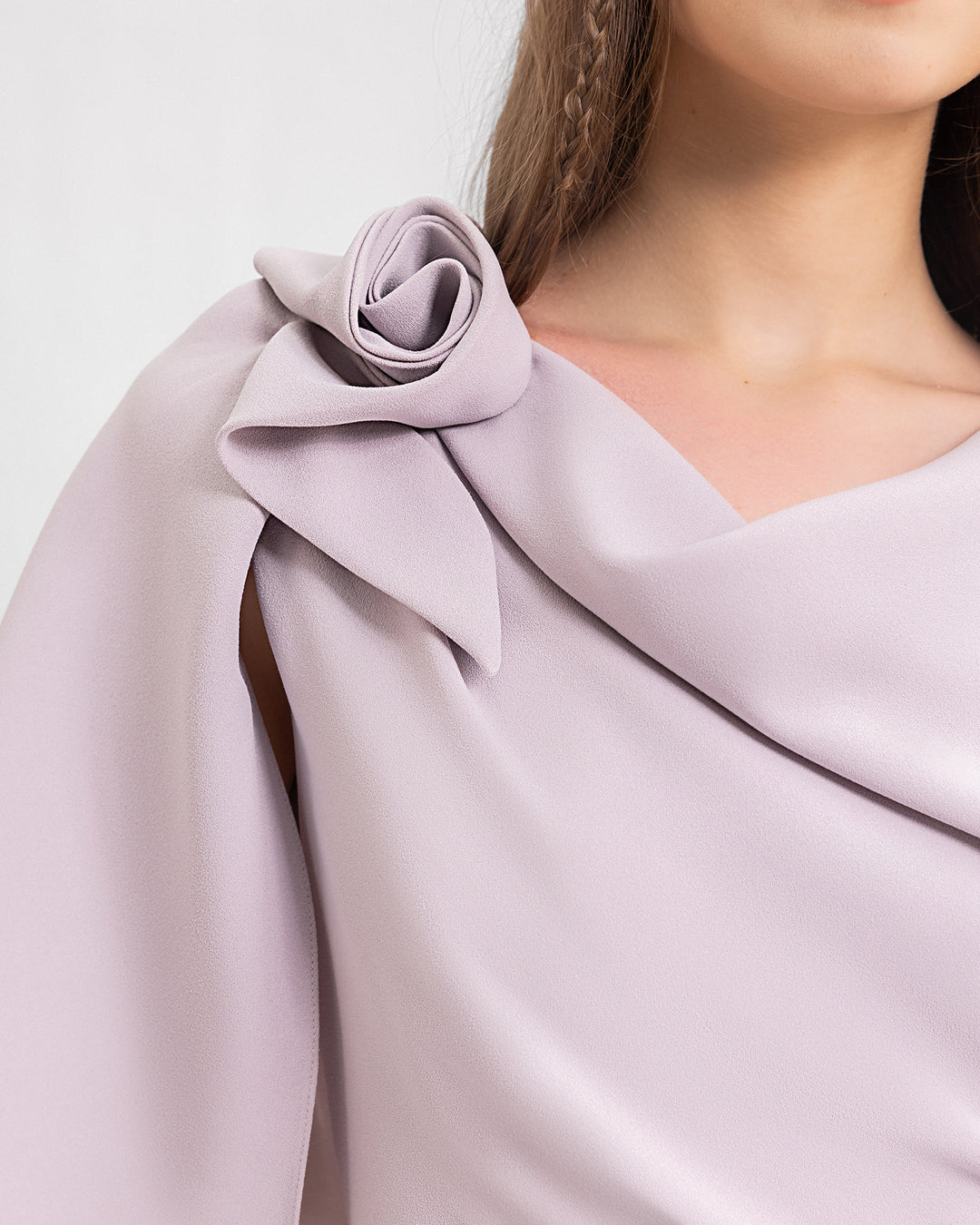 A close-up of an evening dress in dusty pink featuring a draped flower on the shoulder.