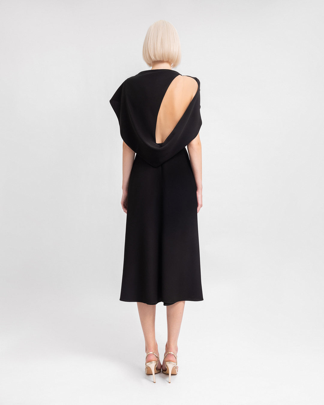 A midi black evening dress with draped sleeves and a cut-out at the back.