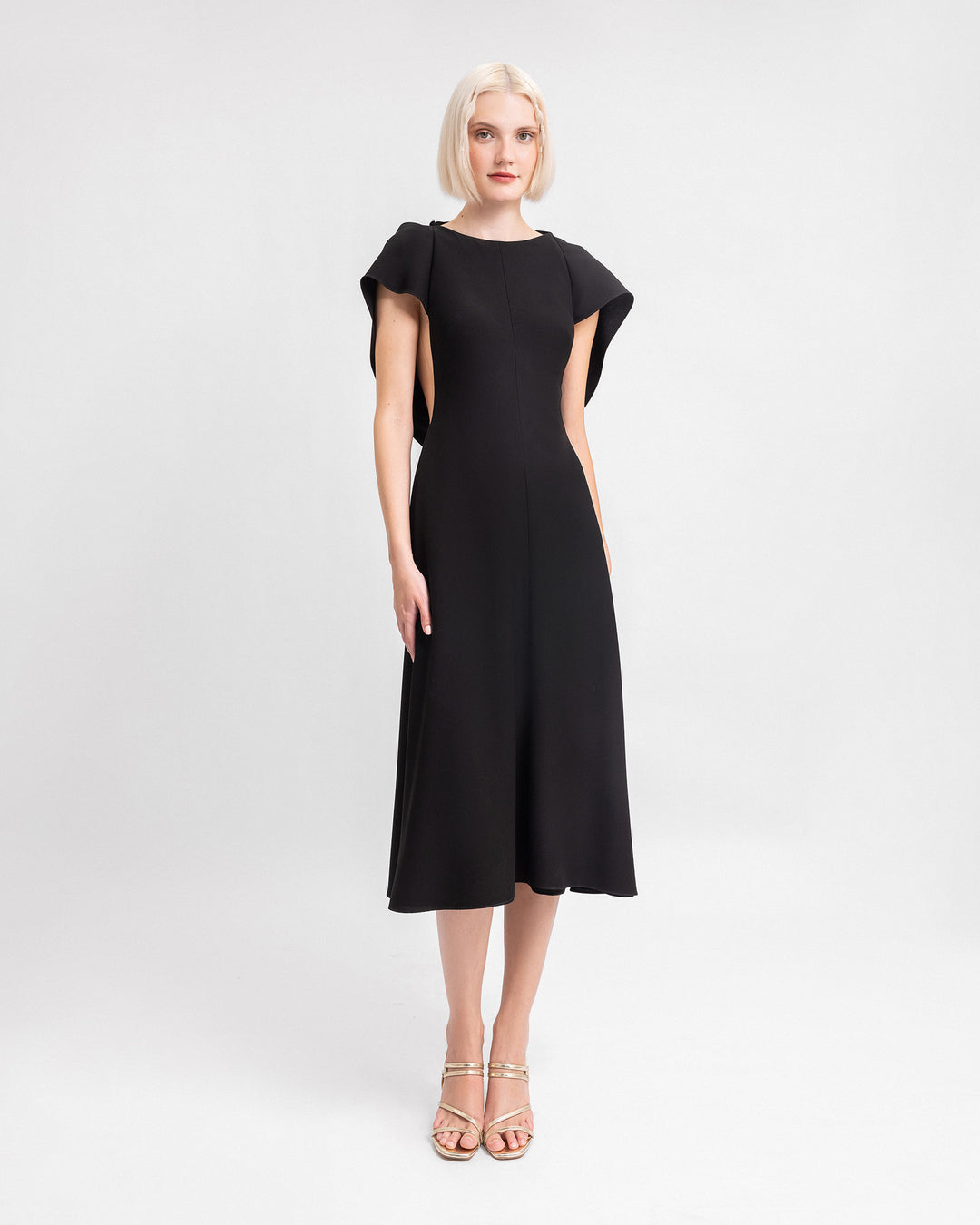 A midi black evening dress with draped sleeves and a cut-out at the back.