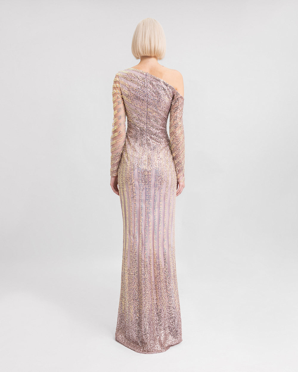 The back of a fully beaded asymmetrical neckline evening dress with long sleeves.