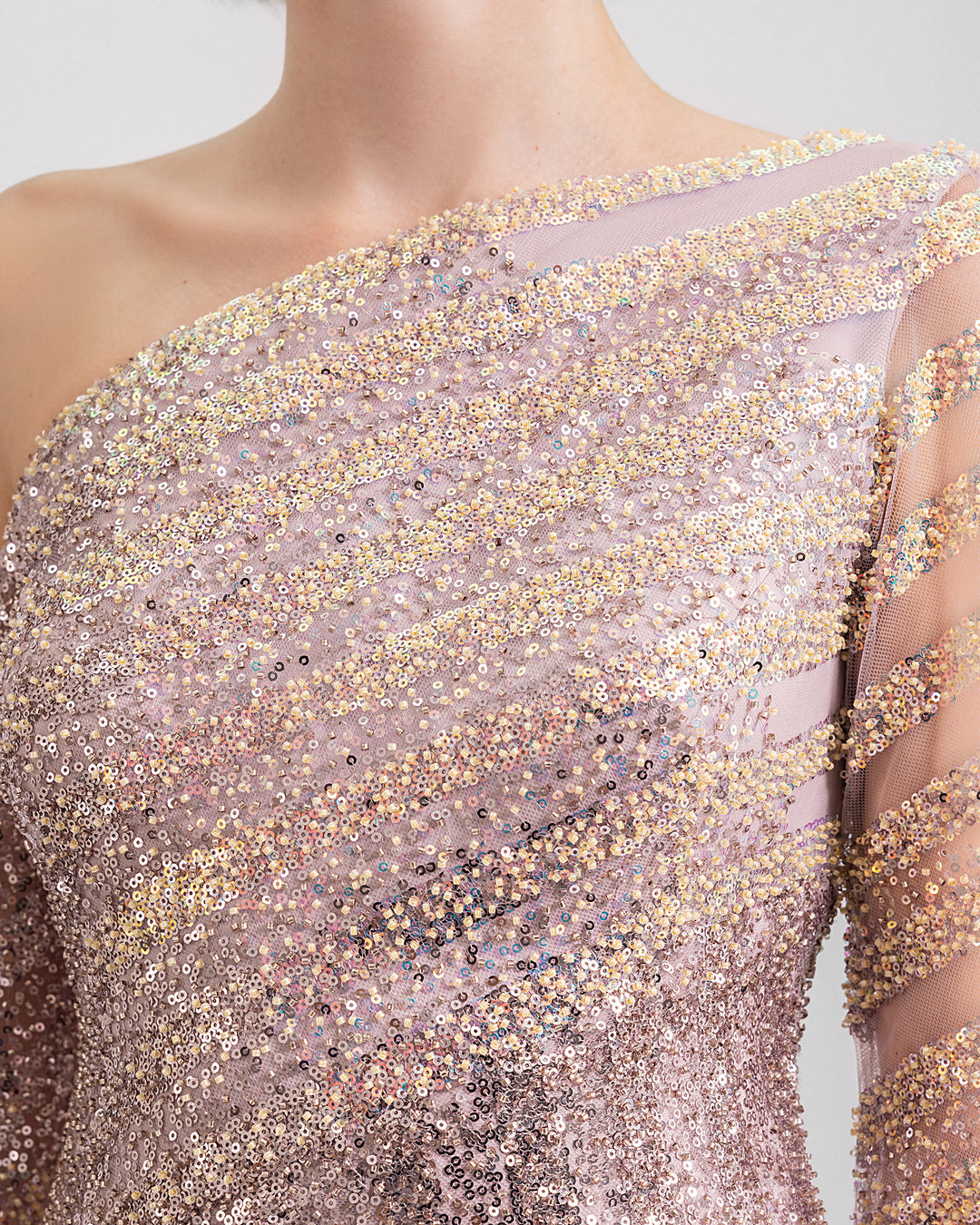 A close-up of a fully beaded asymmetrical neckline evening dress with long sleeves