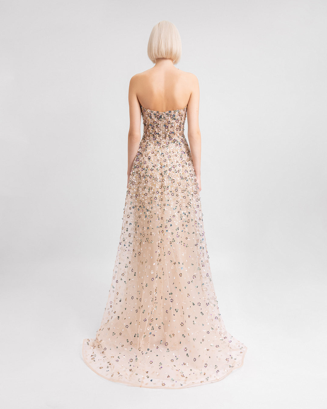 The back of a fully beaded strapless evening dress in beige color with an A-cut skirt.