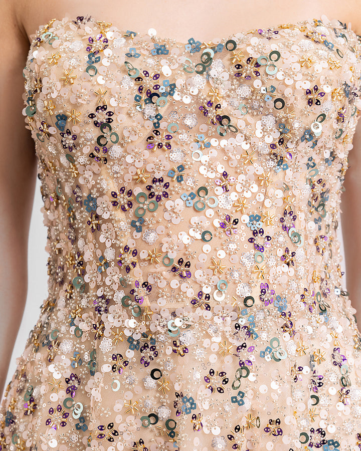 A close-up of a fully beaded strapless evening dress in beige color.