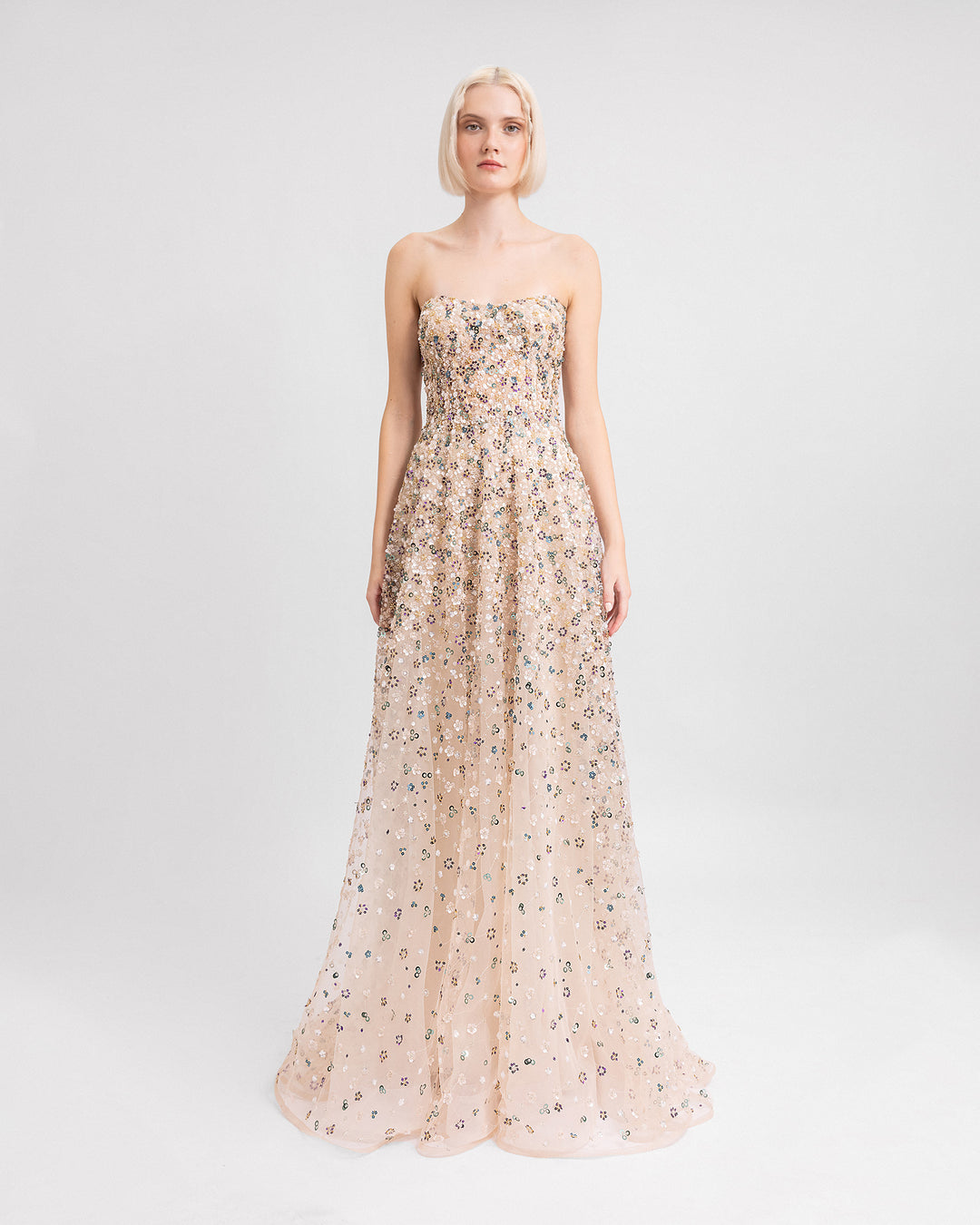 A fully beaded strapless evening dress in beige color with an A-cut skirt.