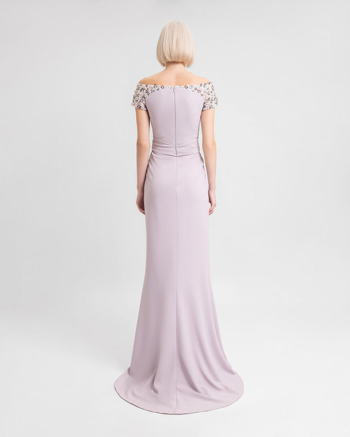 The back of an off-the-shoulders evening dress in dusty pink featuring a draped waistline, and beaded sleeves.