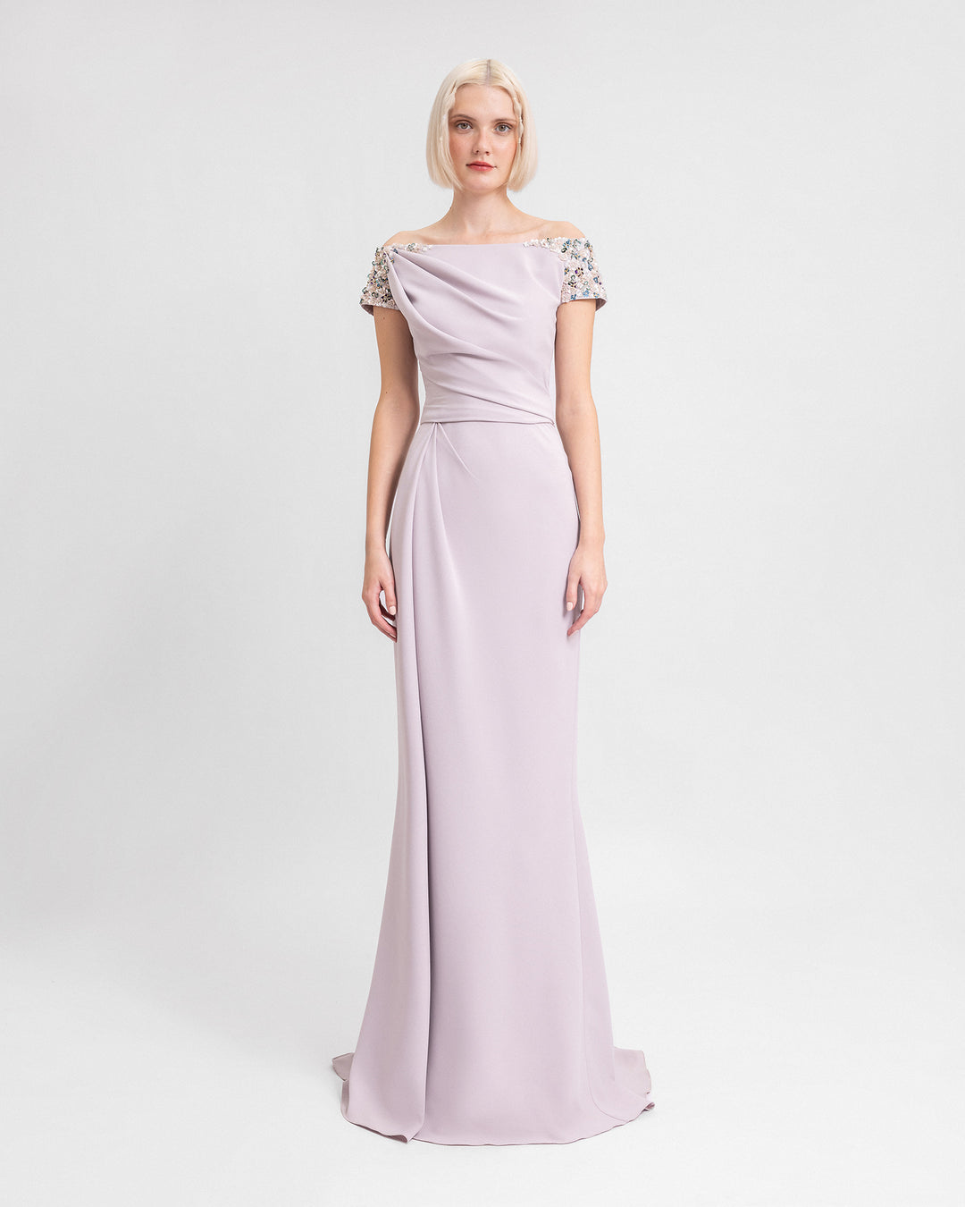 An off-the-shoulders evening dress in dusty pink featuring a draped corset and waistline, and beaded sleeves.