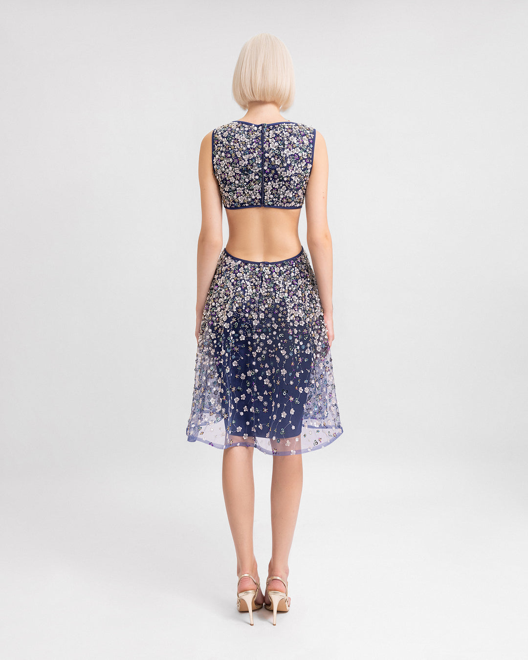 The back of a V-neckline fully beaded short evening dress with cut-outs on the sides and back.