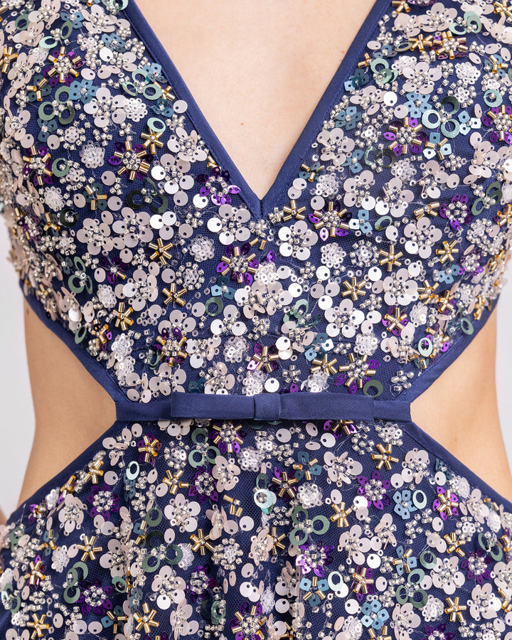 A close-up of a V-neckline fully beaded evening dress with cut-outs on the sides.