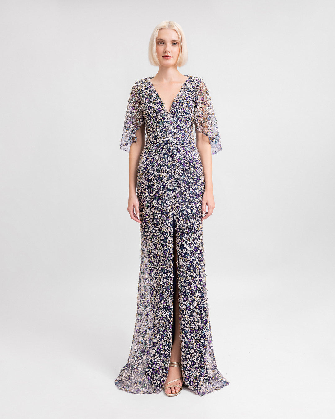 A V-neckline fully beaded evening dress with cape-like sleeves and a slit at the front.