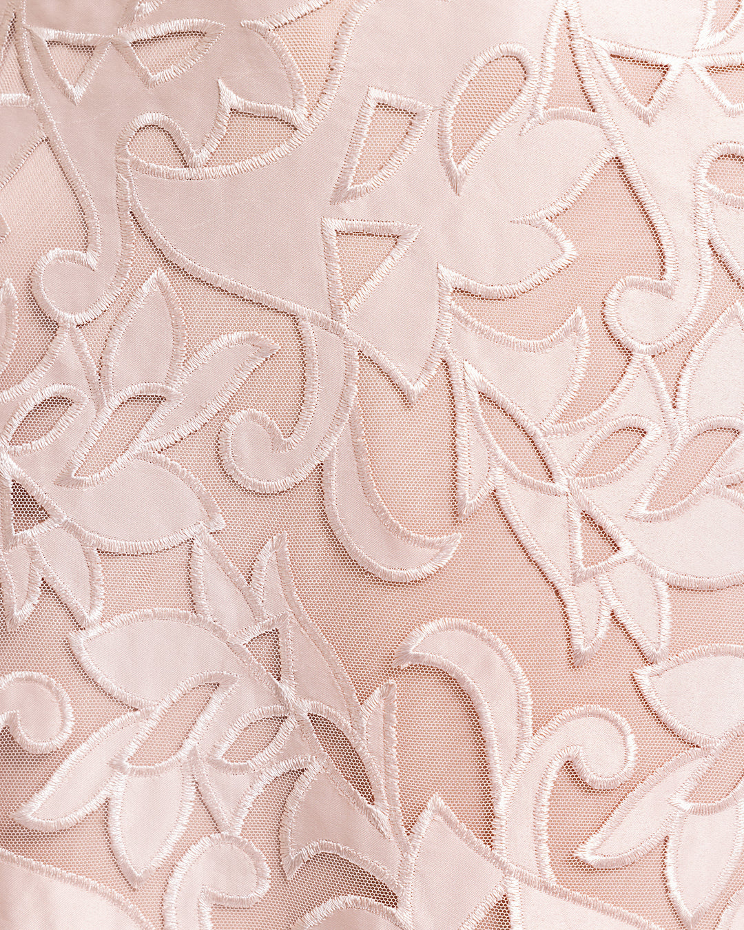 A close-up of an embroidered satin fabric in blush color.