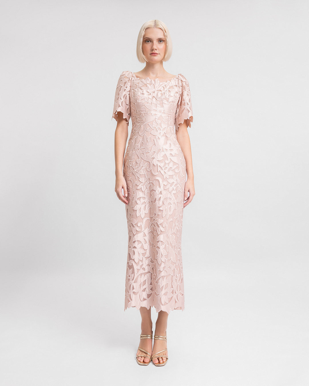 An embroidered satin midi dress in blush color with puffed sleeves and a slit at the back.