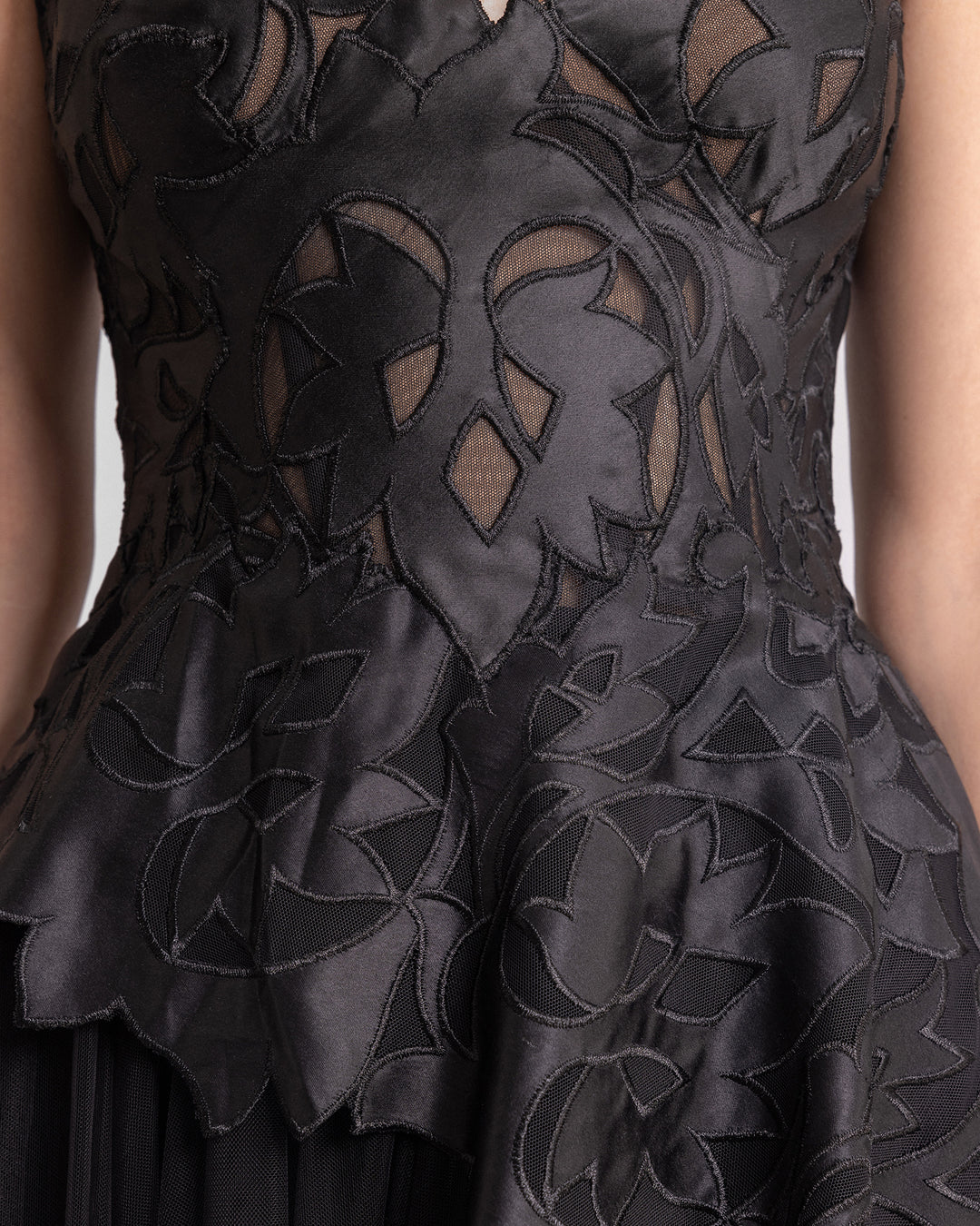 a close-up of a black evening dress featuring an embroidered satin top.