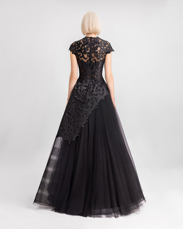 The back of a black evening dress featuring an embroidered satin top with short sleeves and an asymmetrical hemline, paired with a long tulle skirt.