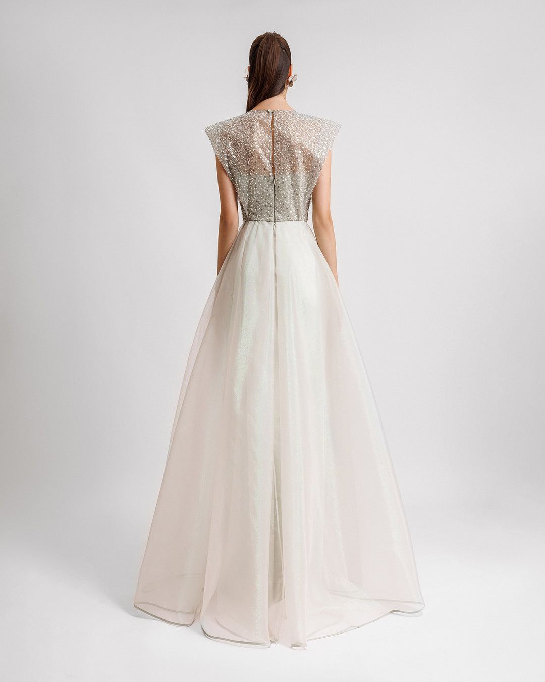 The back of a V-neckline evening dress in light mint green with wide shoulders and an asymmetrical hemline skirt.