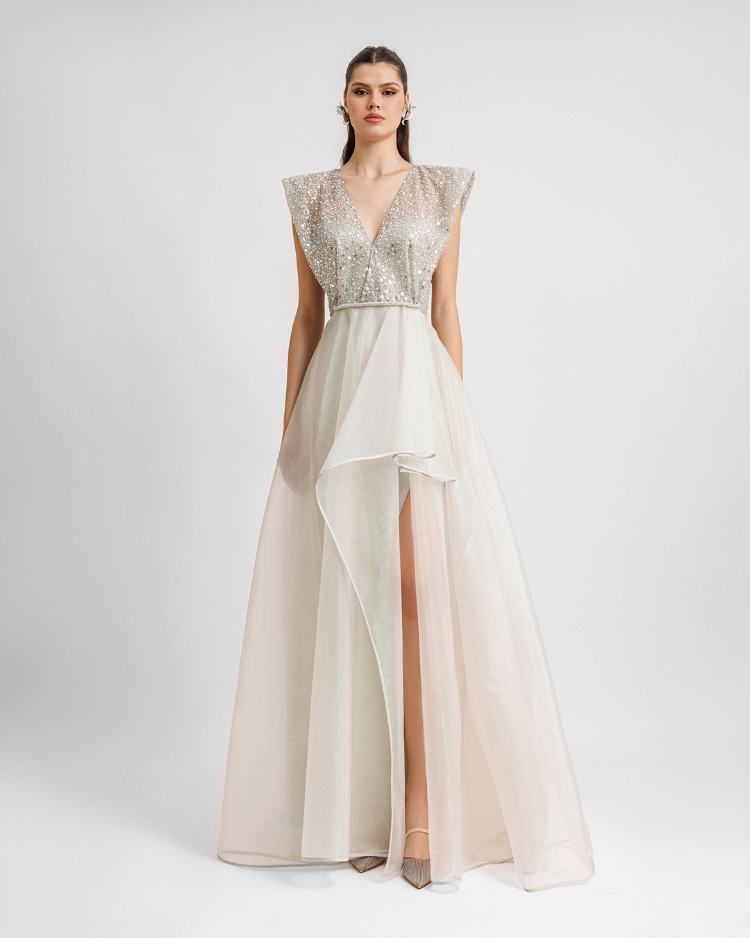 A V-neckline evening dress in light mint green with wide shoulders, a beaded belt on the waist, and an asymmetrical hemline skirt.