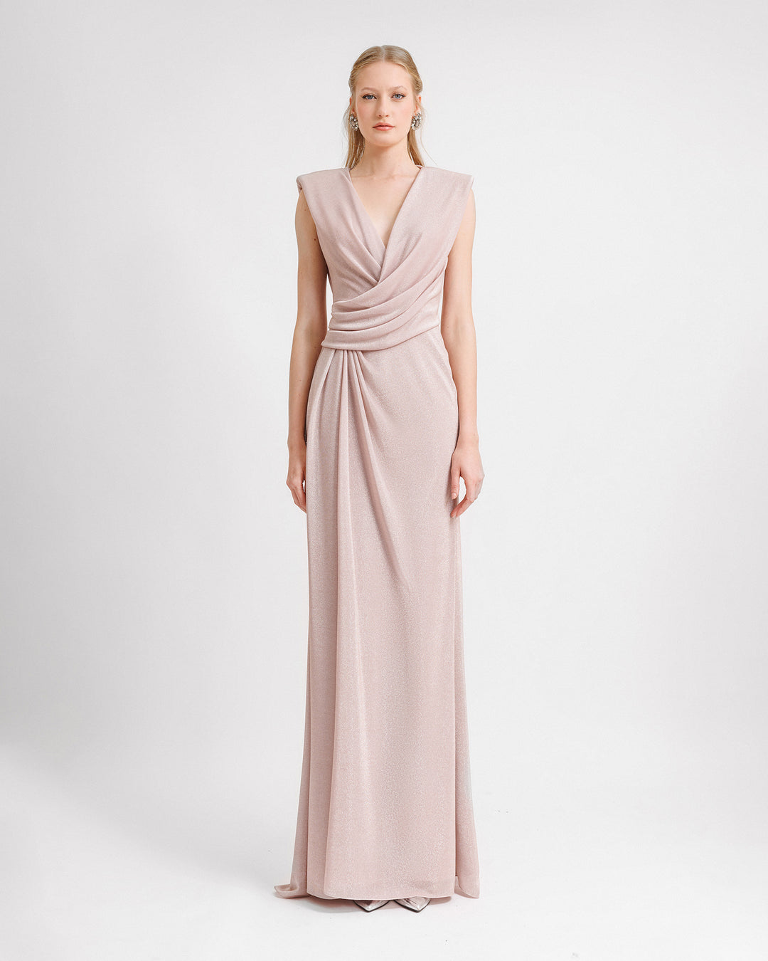 A V-neckline evening dress in blush color with draping at the waist and back.