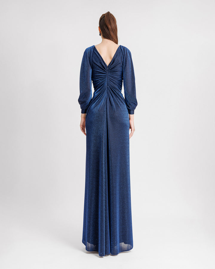 The back of a long sleeves evening dress in midnight blue with a gathered bodice and a V-shaped open back.