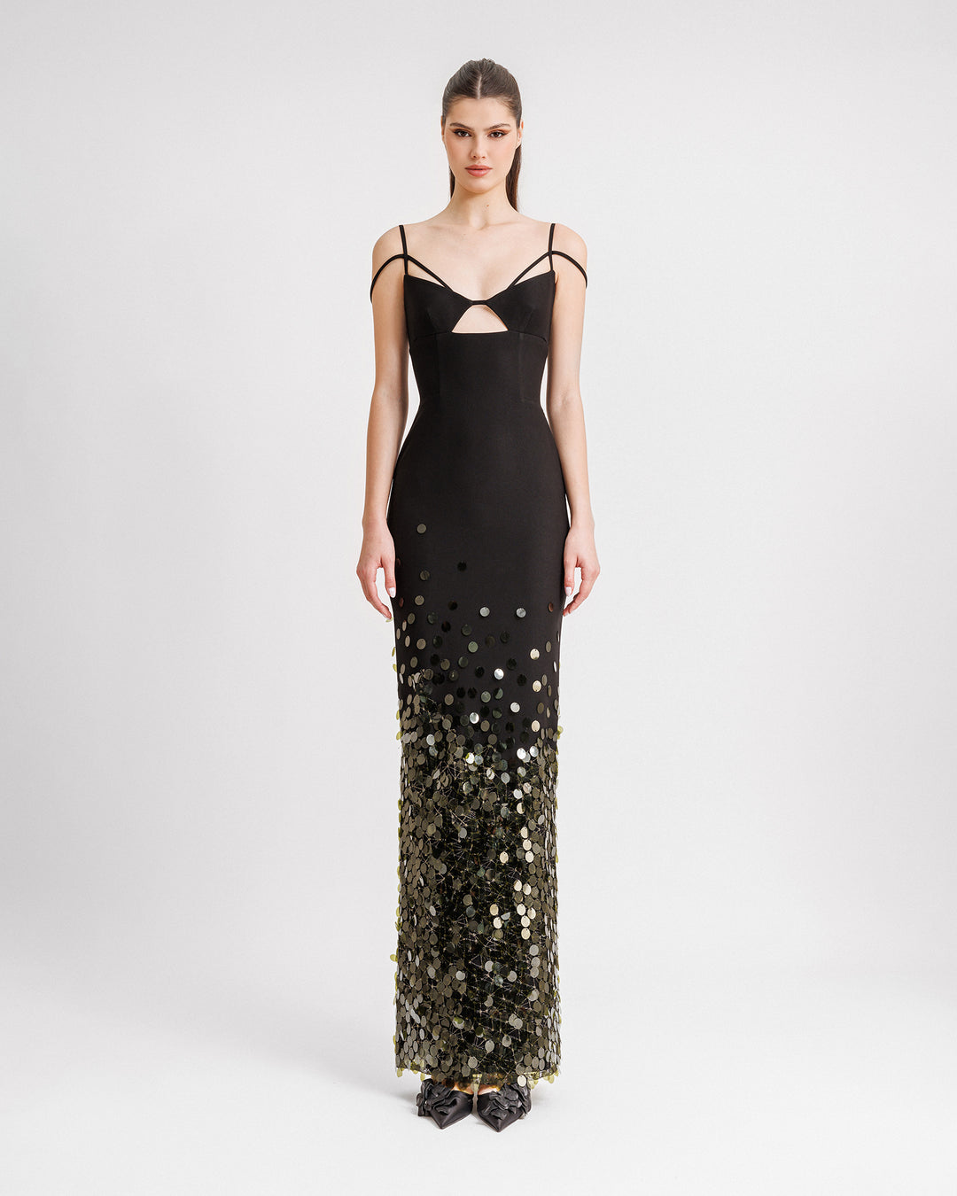 A slim-cut black evening dress with a cut-out at the chest, dropped shoulder straps, and olive sequins degradation to the hemline.