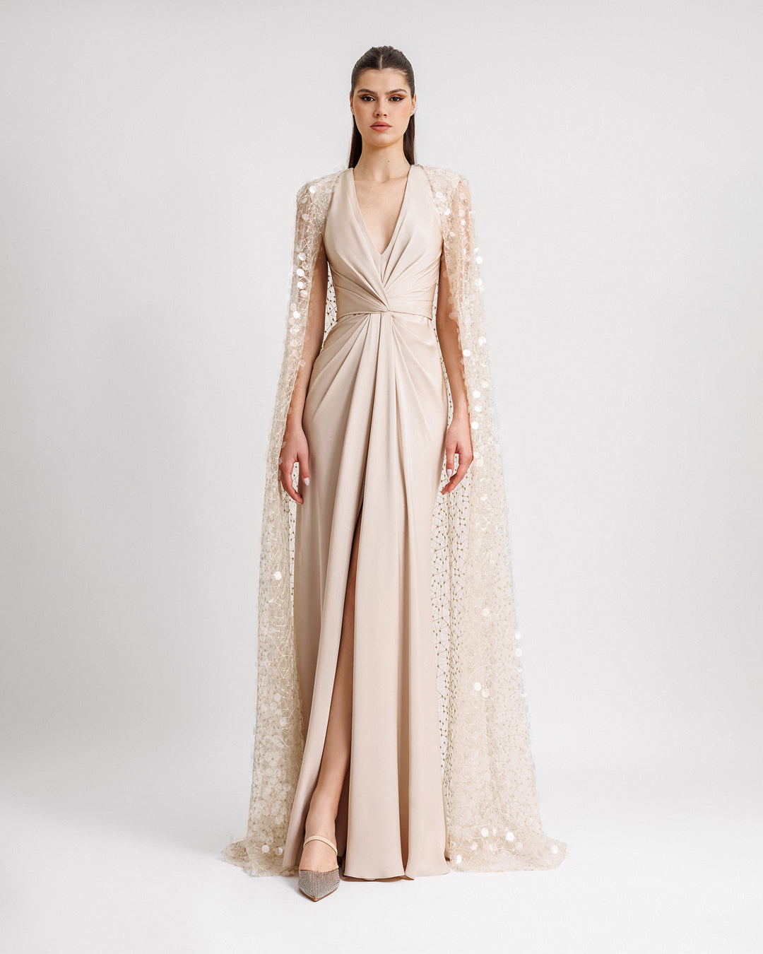 A V-neckline draped bodice evening dress in champagne satin with a slit at the front and a cape in sequins embroidered tulle.