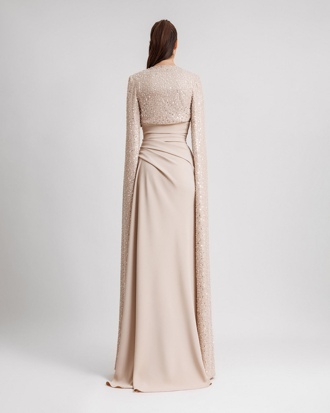 The back of a strapless champagne draped dress with fully beaded floor length sleeves bolero.