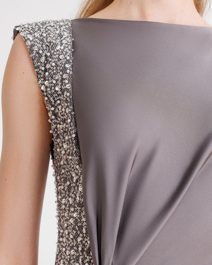 A close-up of a smokey grey evening dress with a beaded stripe on one side.