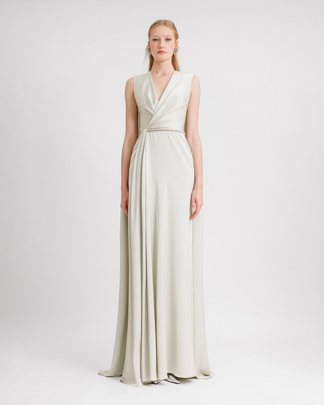 A V-neckline evening dress in light mint satin fabric with draping and a beaded belt on the waist and a cape-like back. 