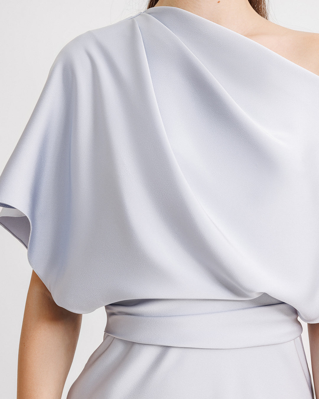 A close-up of an asymmetrical draped neckline evening dress in light blue satin fabric.