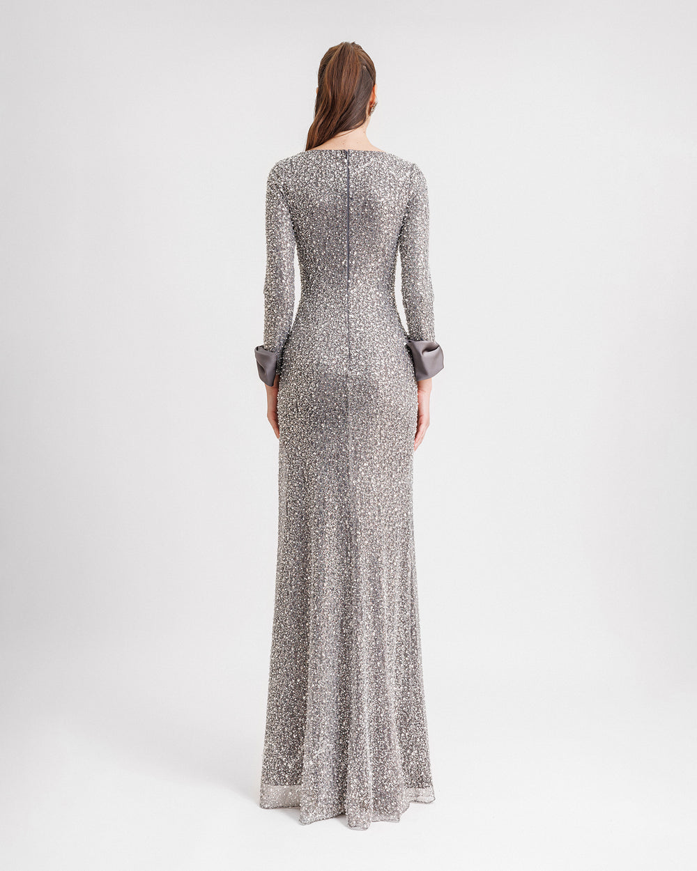 The back of  a slim-cut smokey grey evening dress with satin bows on the wrists.