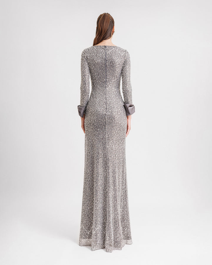 The back of  a slim-cut smokey grey evening dress with satin bows on the wrists.