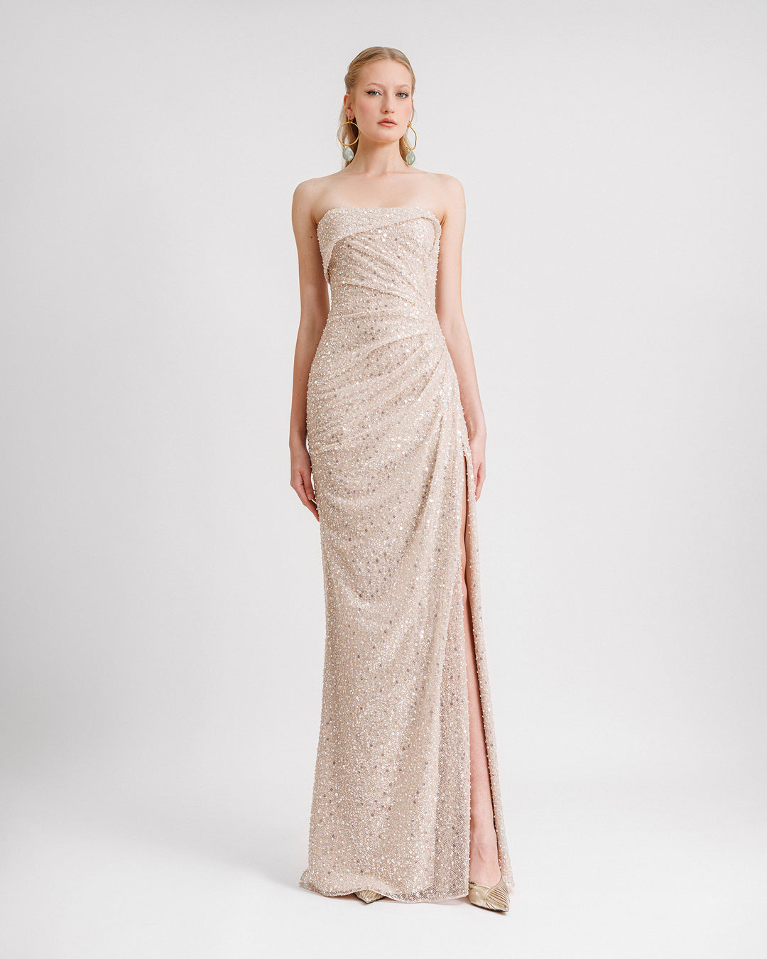 A strapless draped evening dress in champagne beaded tulle with an asymmetrical fold-over neckline and a slit on the side.