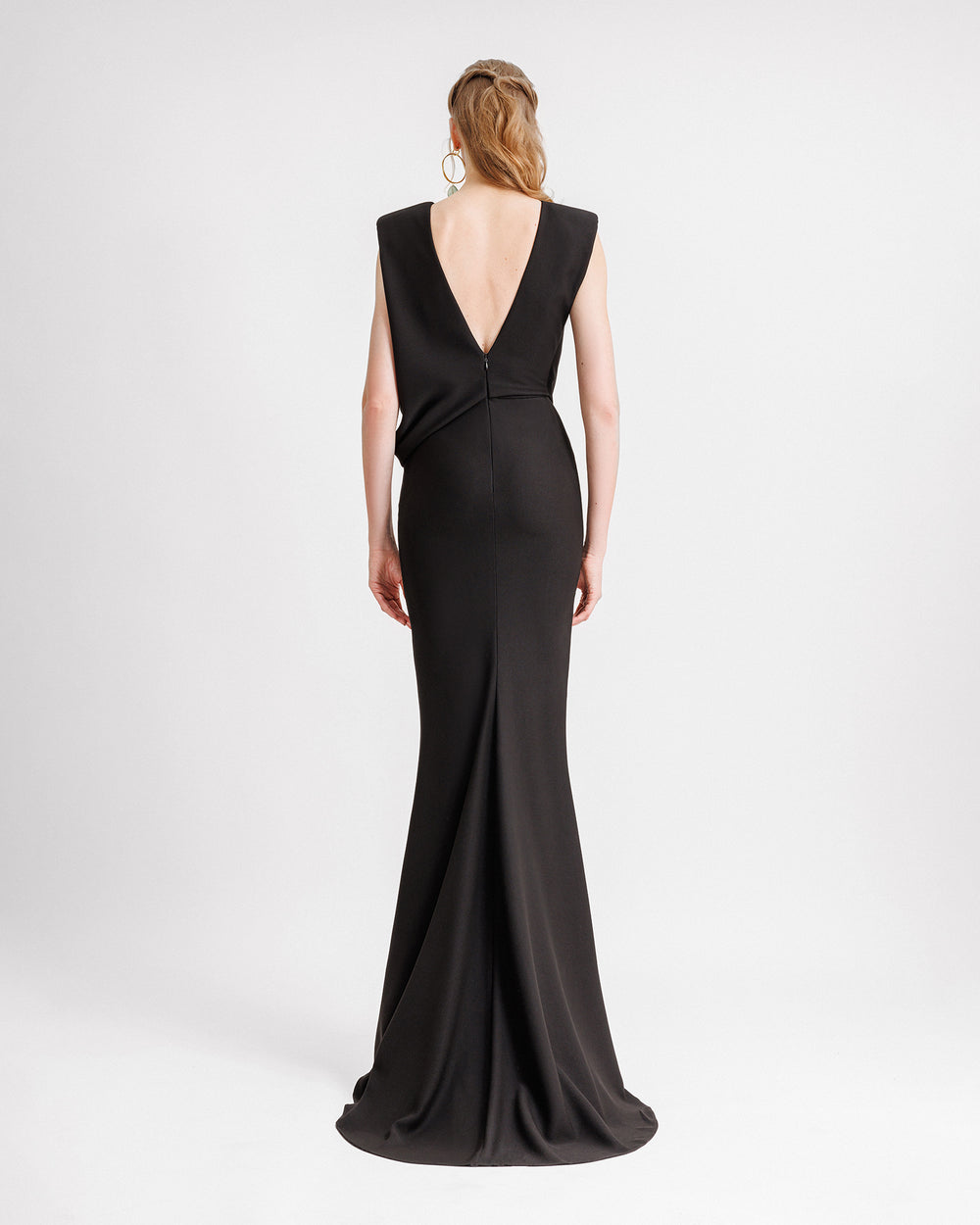 The back of a draped slim-fit black evening dress and a V-shaped open back.