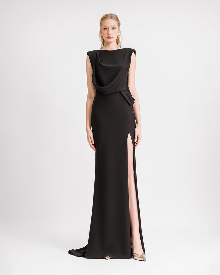 A draped black evening dress with a slit on the side and a low open back.