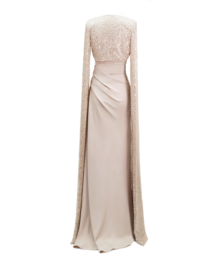 The back of a strapless champagne draped dress with fully beaded floor length sleeves bolero.